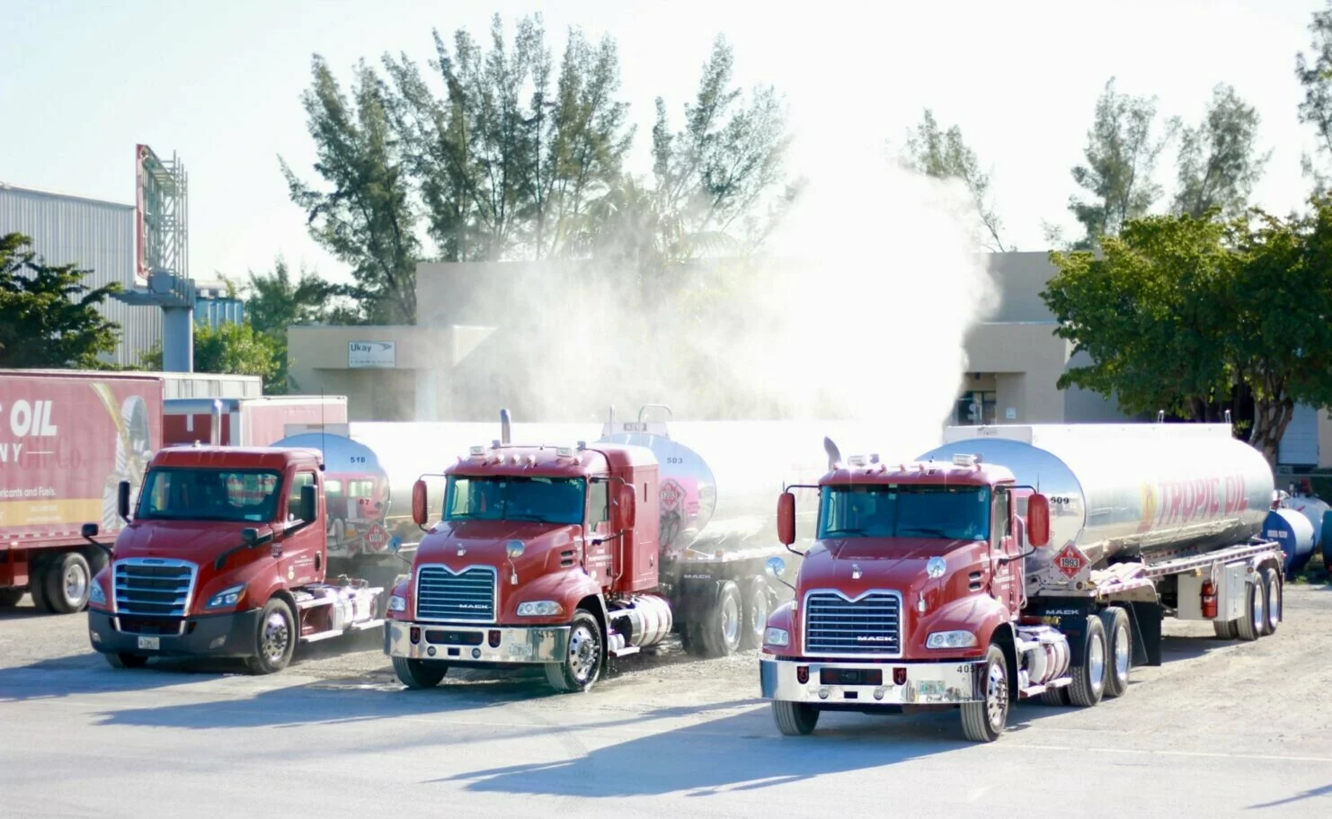 Three red Tropic Oil tanker trucks carrying premium fuel, oil and lubricants in Florida with company name on their tanks.