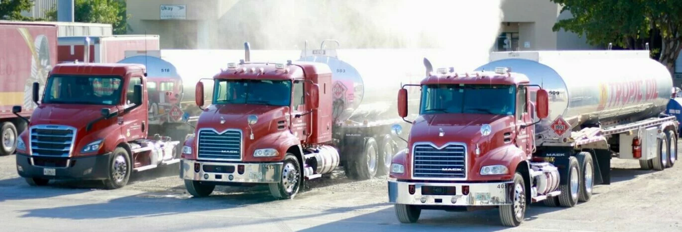 Three red Tropic Oil tanker trucks carrying premium fuel, oil and lubricants in Florida with company name on their tanks.